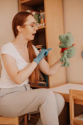 Zdjęcie przedstawiające kobietę trzymającą pluszową zabawkę, badającą zgryz